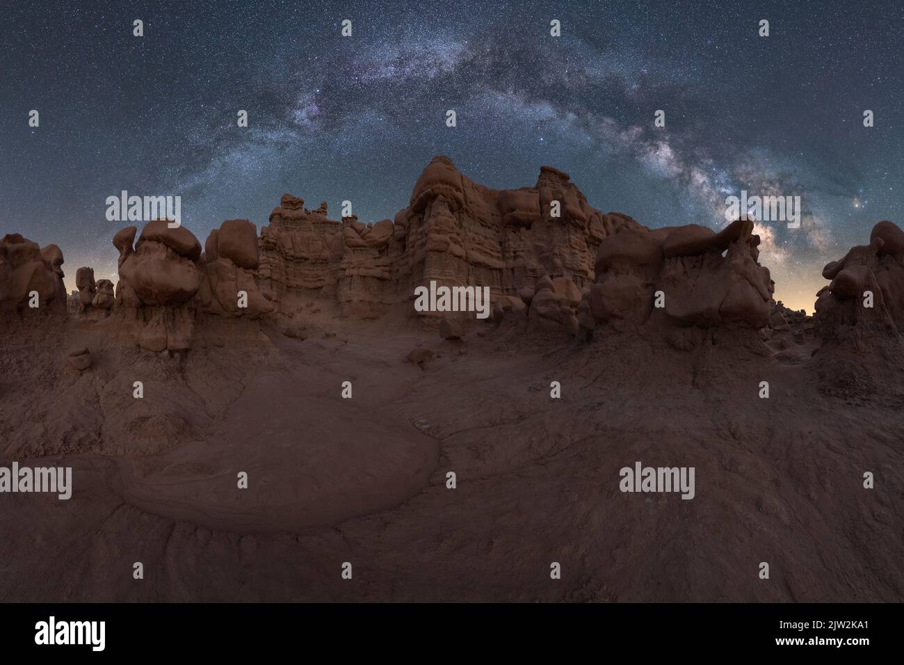 Ungewöhnliche Felsformationen, die sich in der Nähe von Löchern in sandigen Böden in der Nacht in der trockenen Wüste am herrlichen Sternenhimmel befinden Stockfoto