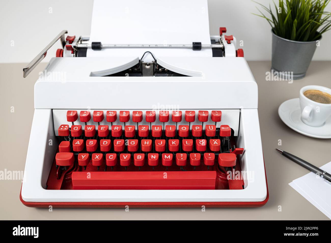 Rot-weiße Schreibmaschine mit leerem Papier auf dem Schreibtisch. Kreatives Schreiben Texter Konzept Stockfoto