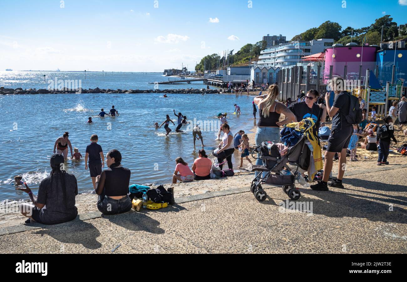 Die Menschen sitzen in der Sonne am Rande der drei Muscheln Lagune an der Küste in Southend-on-Sea, Essex, Großbritannien. Stockfoto