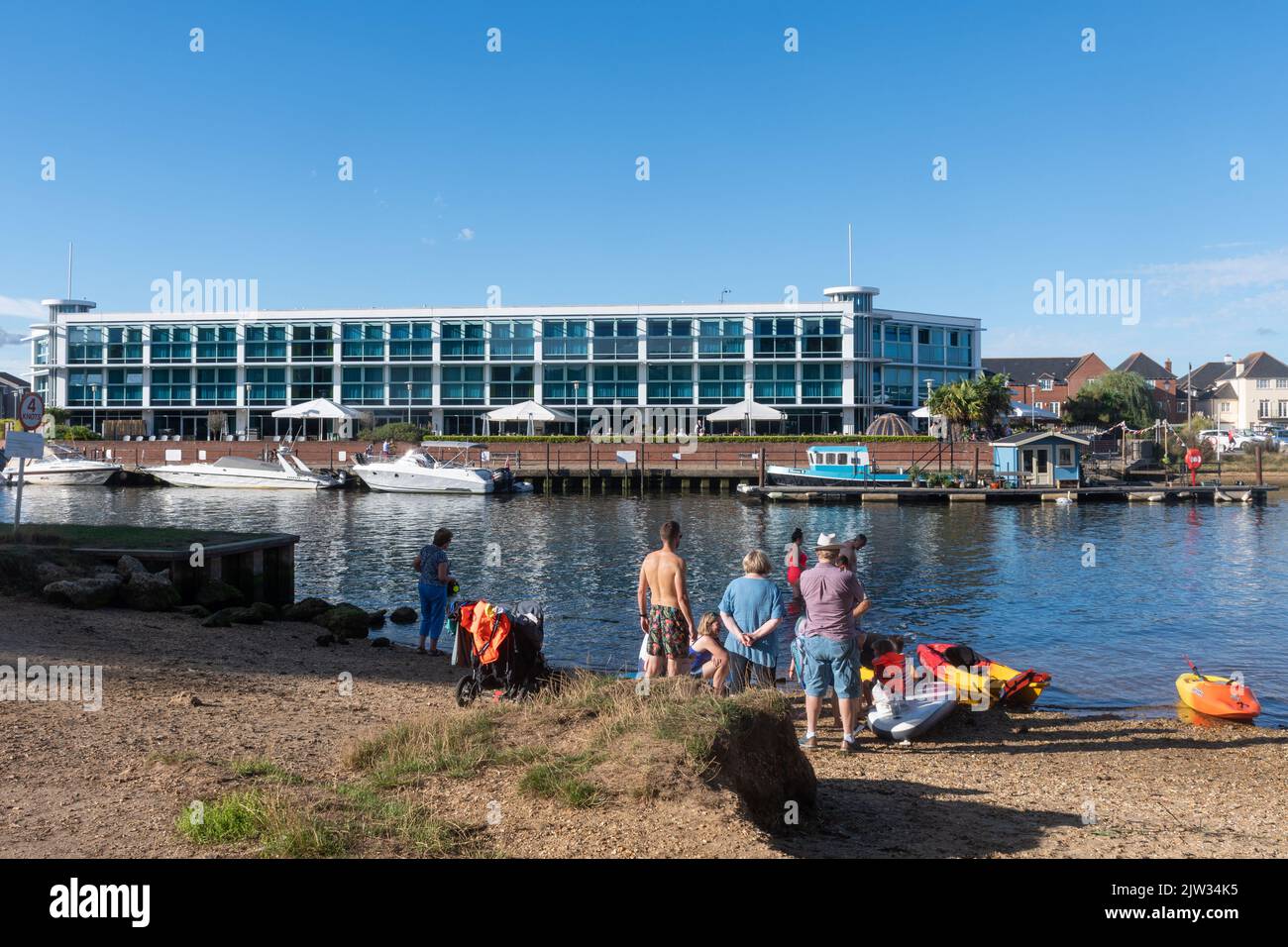 Menschen in den Sommerferien am Fluss Stour mit dem Captain's Club Hotel im Hintergrund, Christchurch, Dorset, England, Großbritannien Stockfoto