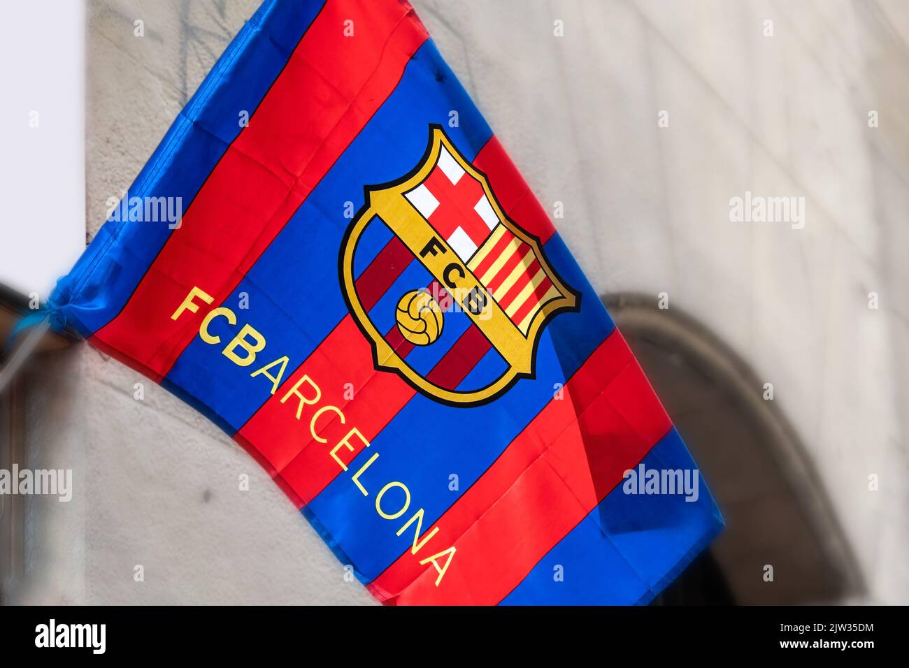 Blick aus der Nähe auf einen Football Club Barcelona oder FCB. Das Textilsymbol winkt im Wind vor der Tür eines privaten kleinen Souvenirladens Stockfoto