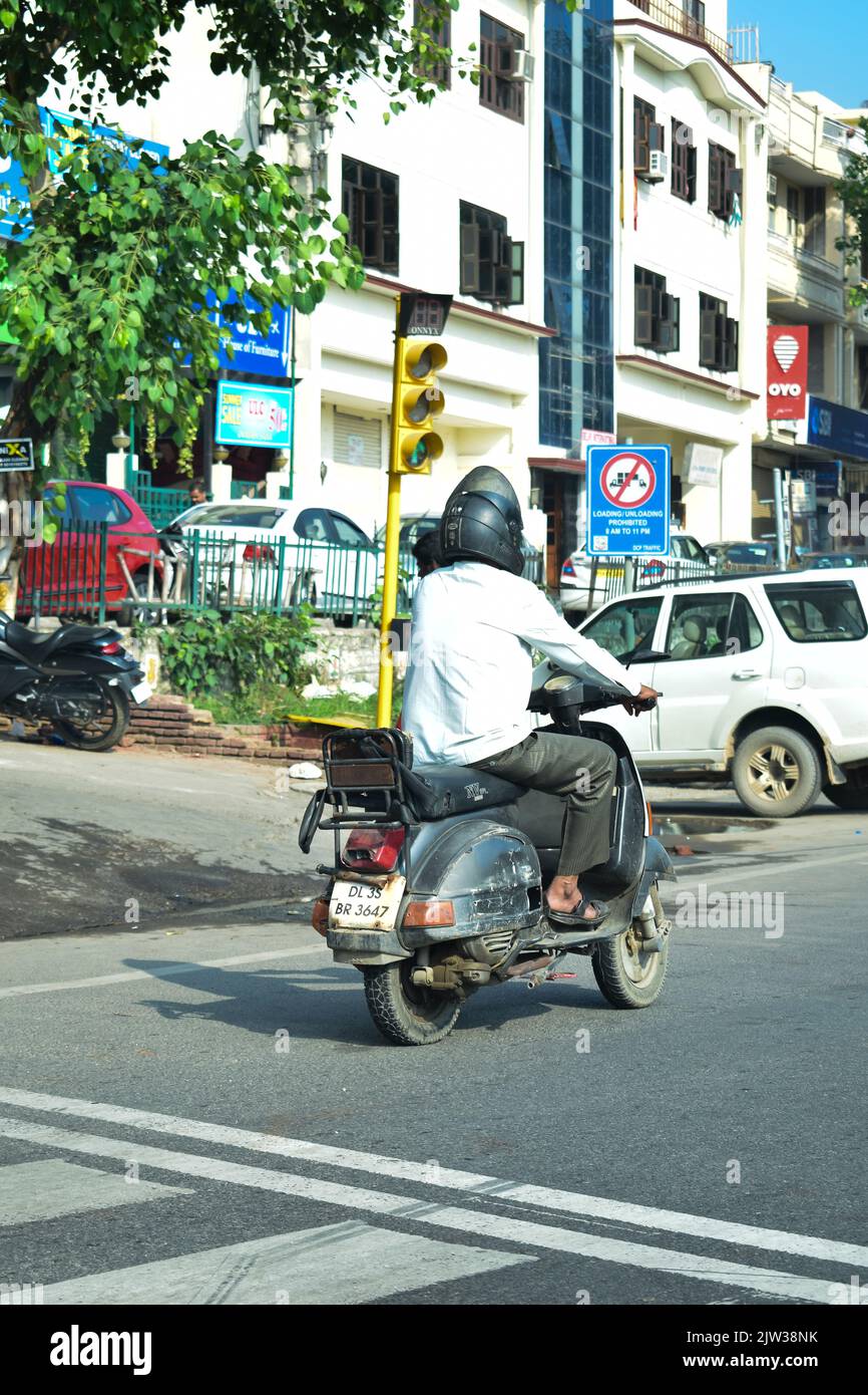 Indischer Mann, der auf der Straße Scooter reitet. Stockfoto