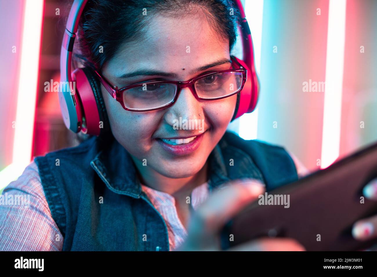 Nahaufnahme von Mädchen mit Kopfhörer und Brillen spielen Online-Videospiel auf Handy zu Hause - Konzept der Live-Streamer, Urlaub und Stockfoto
