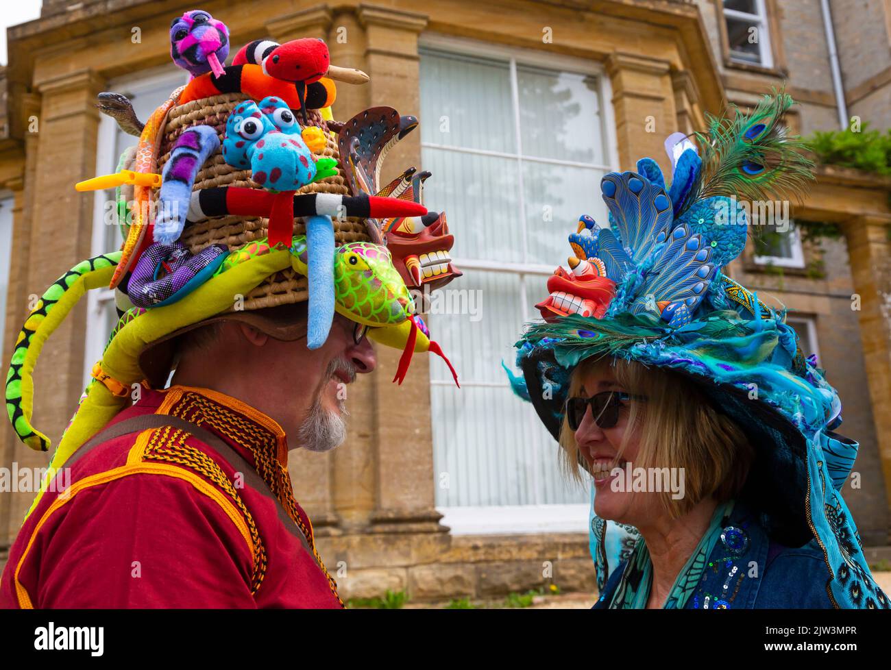 Bridport, Dorset, Großbritannien. 3.. September 2022. Eine Vielzahl von Stil und schrulligen Hüten, die von Menschen und Hunden beim Bridport hat Festival in Dorset hergestellt und getragen werden. Mann mit Hut und Schlangen auf die Frau mit Hut mit Pfau auf. Quelle: Carolyn Jenkins/Alamy Live News Stockfoto