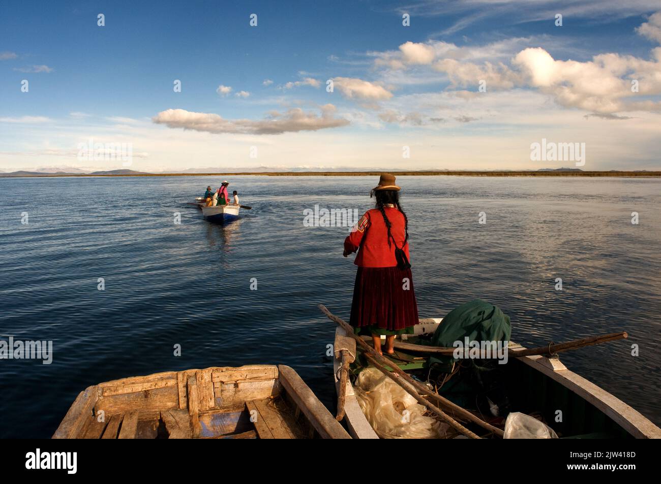 Insel Uros, Titicacasee, peru, Südamerika. Eine Frau in einem Boot auf dem Titicacasee. Der Klimawandel hat das Niveau des Titicacasees, des Hochgebirgssees, gesenkt Stockfoto