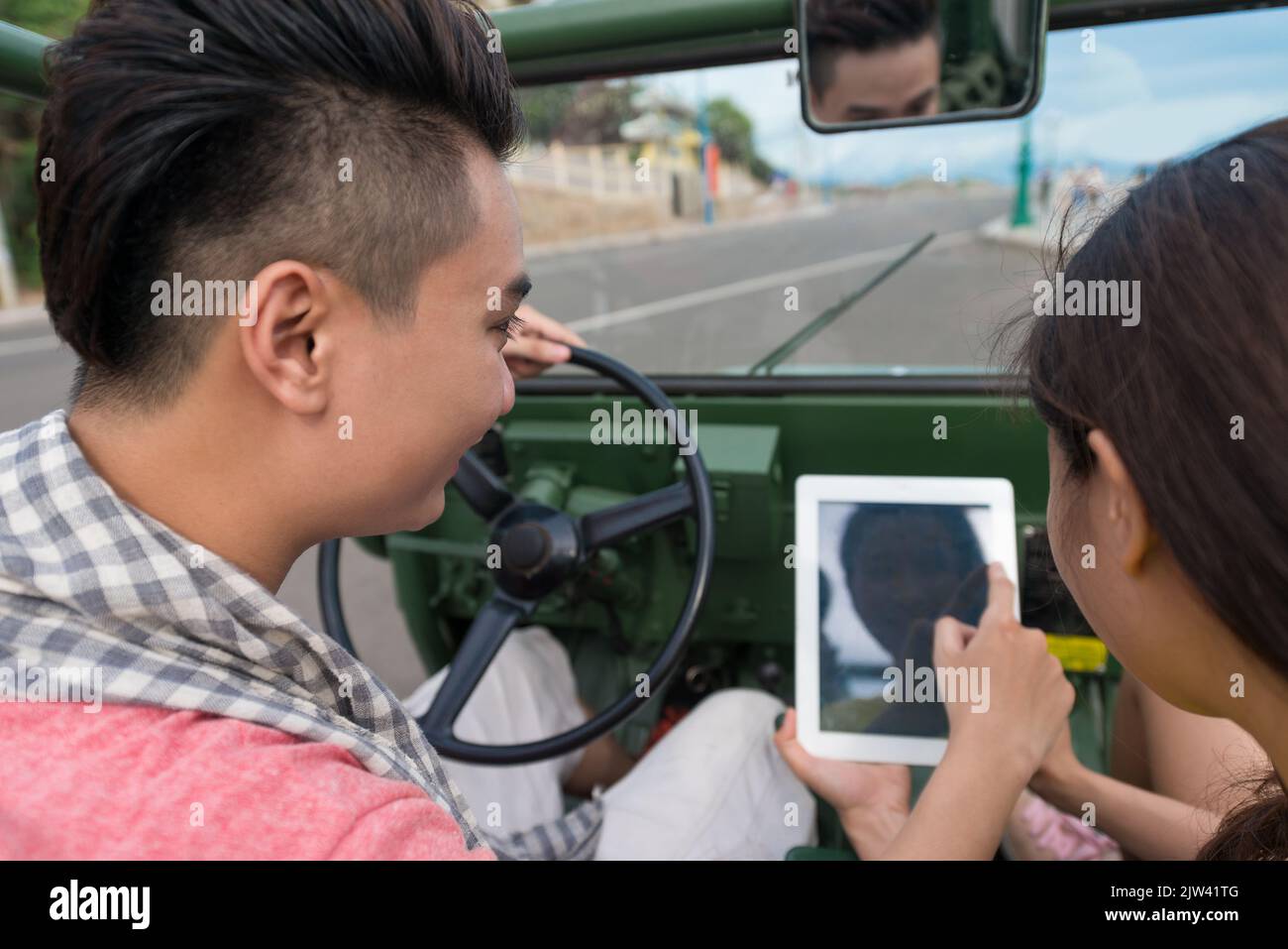 Junges Paar, das während der Fahrt mit dem Auto über das Touchpad kommuniziert Stockfoto