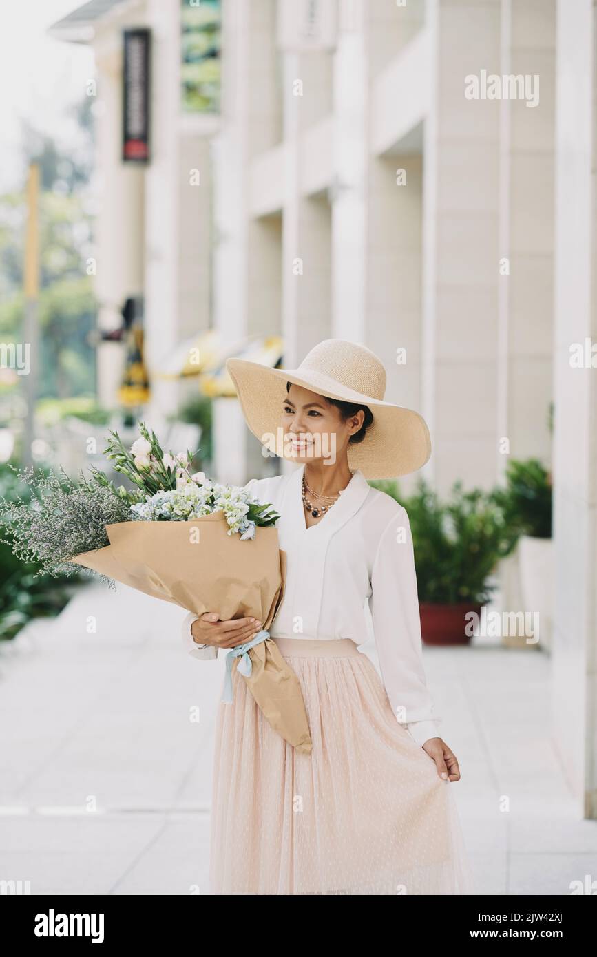 Attraktive junge Frau im Sommerhut mit einem großen Strauß Stockfoto