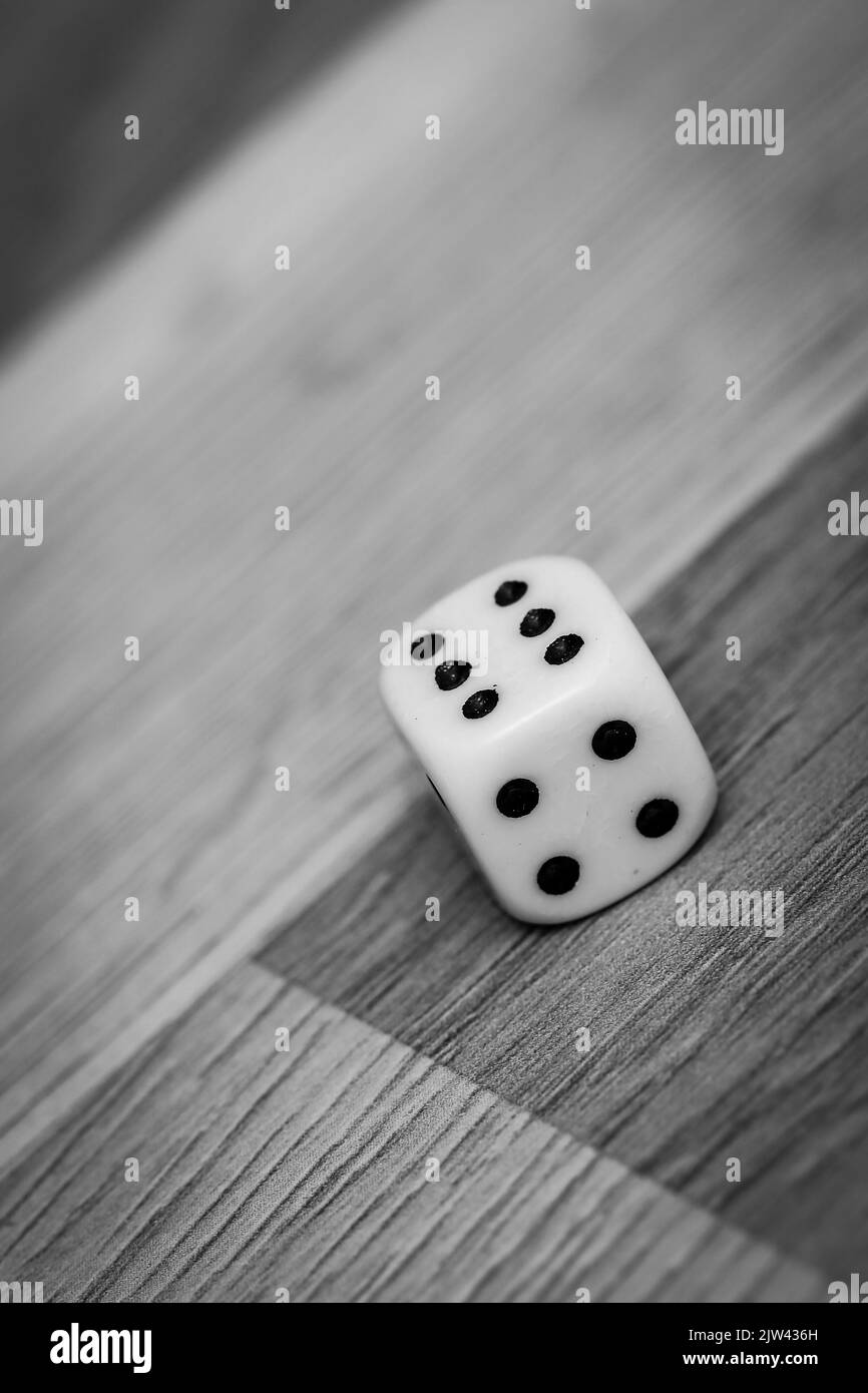 Weiße Spielwürfel mit der Nummer sechs auf dem Boden, schwarz-weißes Bild Stockfoto