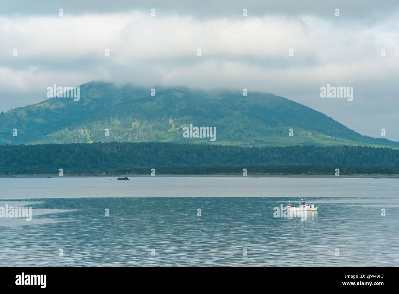 Meeresbucht mit nebligen Bergen im Hintergrund, Blick auf den Mendelejew-Vulkan an einem bewölkten Tag Stockfoto