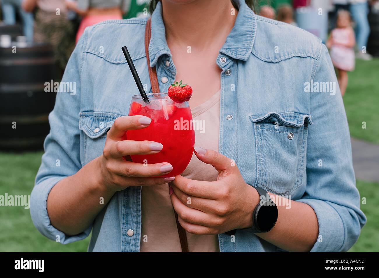 Junge Frau trinkt Erdbeer-Daiquiri-Cocktail oder Mocktail im Glas mit Trinkhalm zu Sommerfestlichkeiten. Erfrischender Sommerdrink für Party oder feten Stockfoto