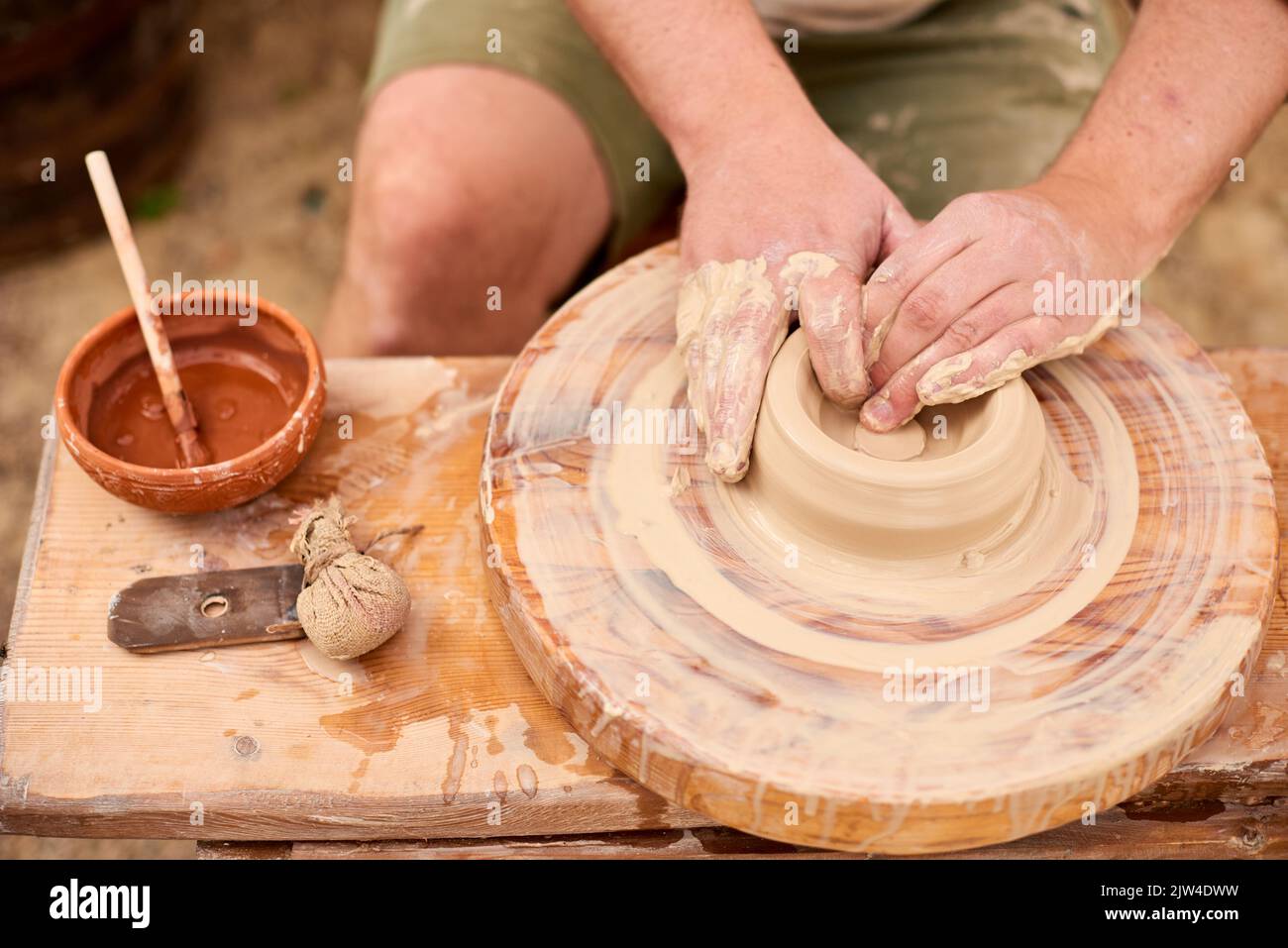 Nahaufnahme männliche Hände in der Arbeit mit weißem Ton. Meister in hellem Leinenhemd machen Schüssel Stockfoto