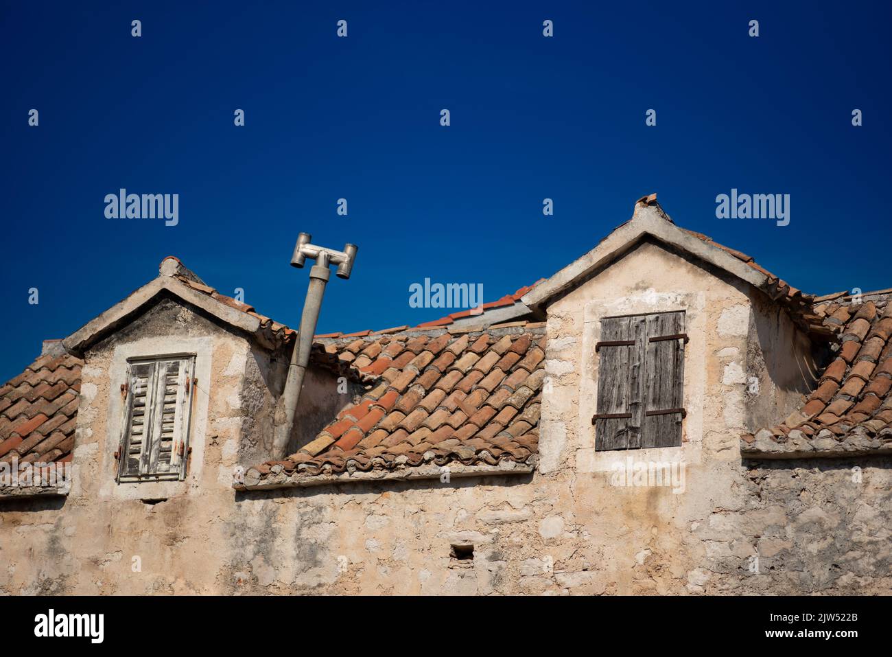 Das Dach eines alten Hauses mit zwei Dachfenstern und einem kleinen Kamin Stockfoto