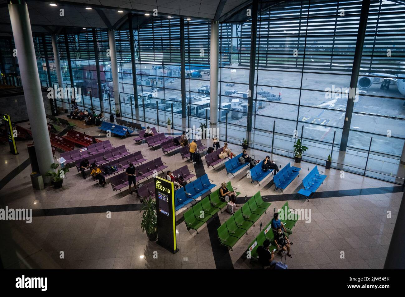 Passagiere werden auf bunten Bänken am internationalen Flughafen Phnom Penh (PNH) auf ihre Flüge warten sehen. Szenen am Phnom Penh International Airport (PNH) während eines stadtweiten Stromausfalls. Stockfoto