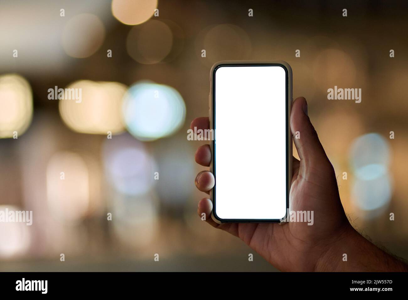 Männliche Hand hält Smartphone mit weißem Bildschirm auf Nacht Stadt Hintergrund. Stockfoto