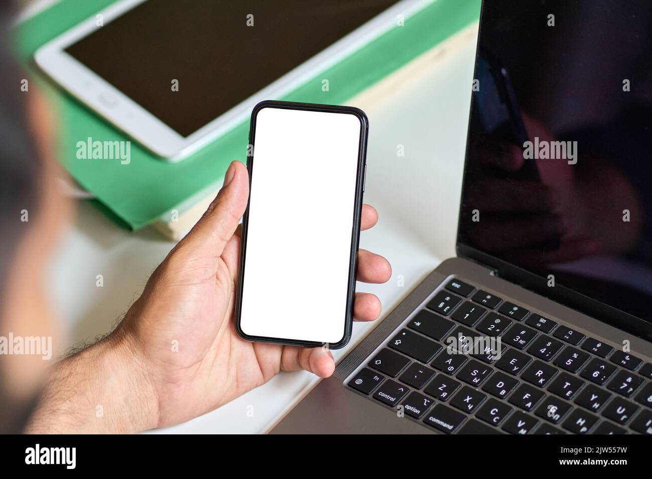 Geschäftsmann, der bei der Arbeit ein Mobiltelefon mit einem weißen Bildschirm hält. Stockfoto