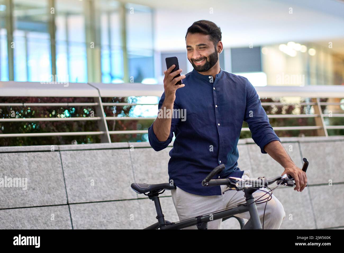 Indischer Mann, der per Telefon Fahrrad-Verleih-App Fahrrad im Stadtpark ausleihen kann. Stockfoto