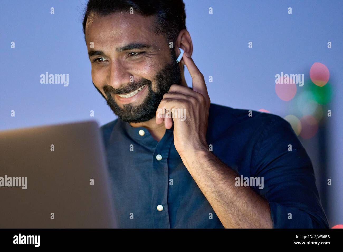 Lächelnder indischer Geschäftsmann, der nachts einen virtuellen Meeting-Videoanruf hat. Stockfoto