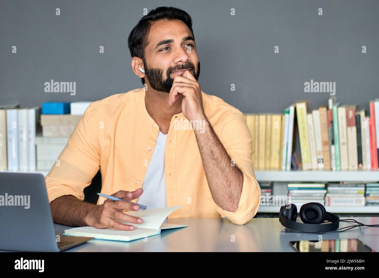 Nachdenklicher indischer Geschäftsmann, der im Heimbüro mitarbeitet und denkt, ihm zuzuhören. Stockfoto