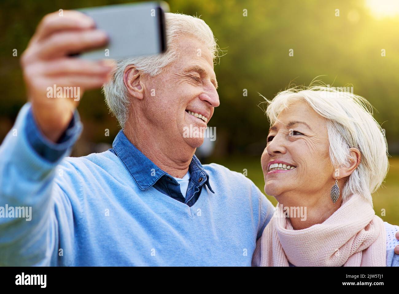 Erinnerungen festhalten. Ein Seniorenpaar fotografiert gemeinsam in einem Park. Stockfoto