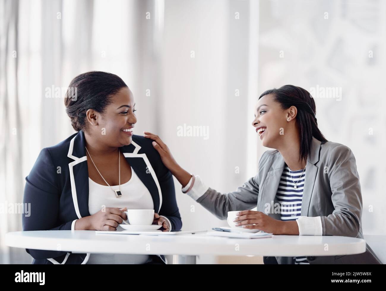 Das ist urkomisch: Zwei attraktive junge Geschäftsfrauen lachen, während sie in ihrem Büro zusammenarbeiten. Stockfoto