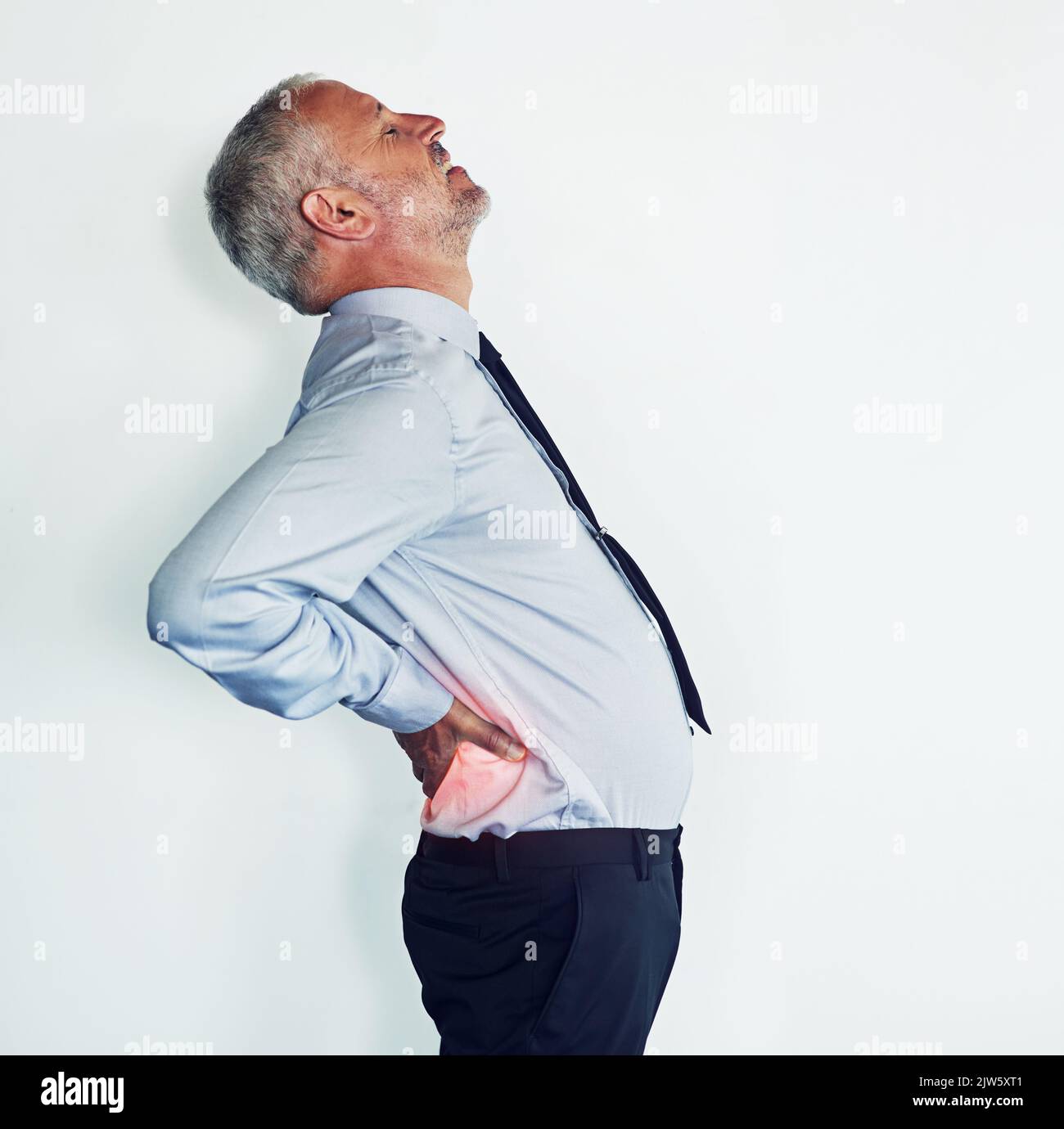 Sich nach hinten beugen, um die Arbeit zu erledigen. Studioaufnahme eines reifen Mannes, der muskuläre Belastungen erlebt. Stockfoto