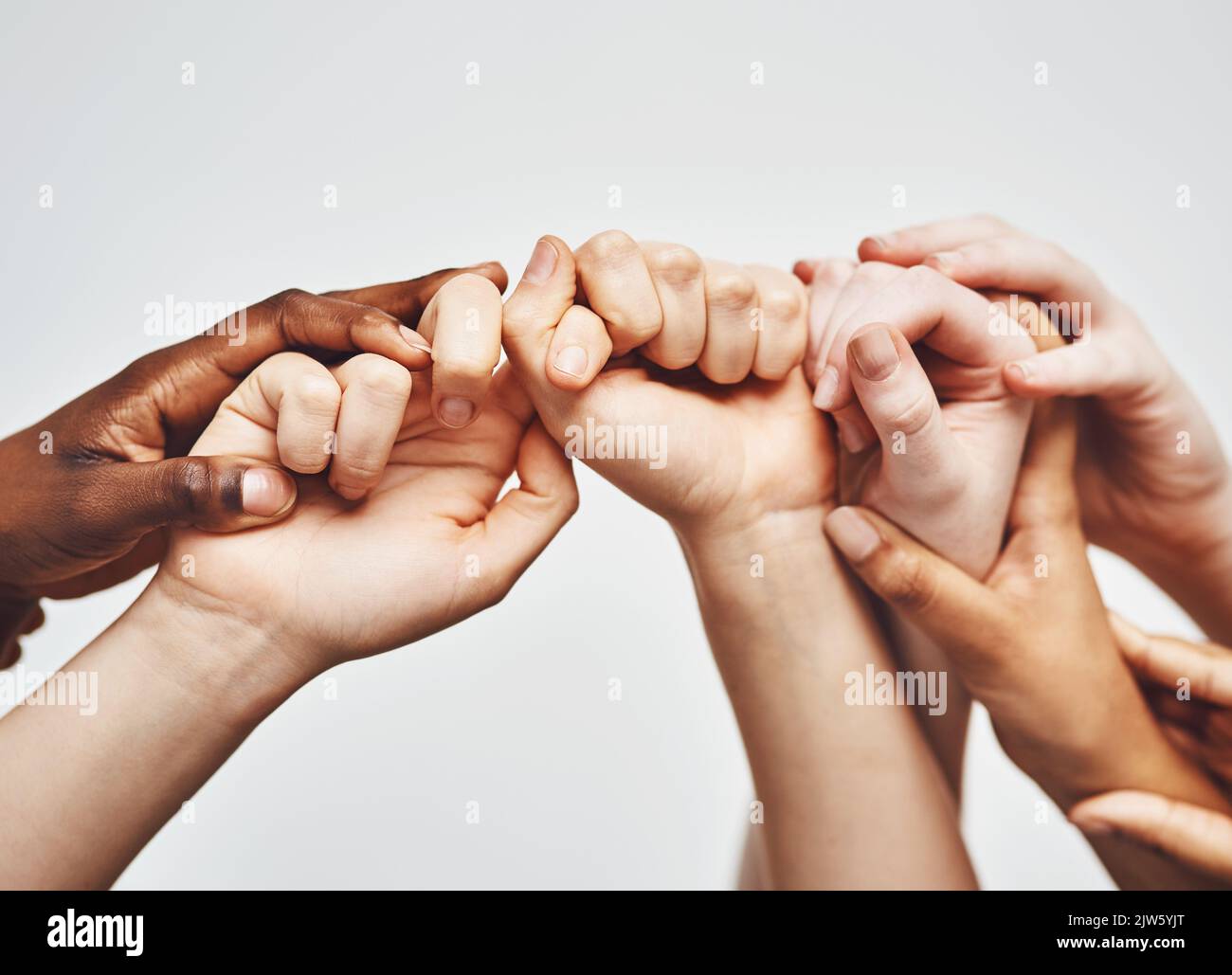 Halten Sie sich nur ein wenig länger fest. Eine Gruppe von Händen, die sich vor einem weißen Hintergrund aneinander halten. Stockfoto