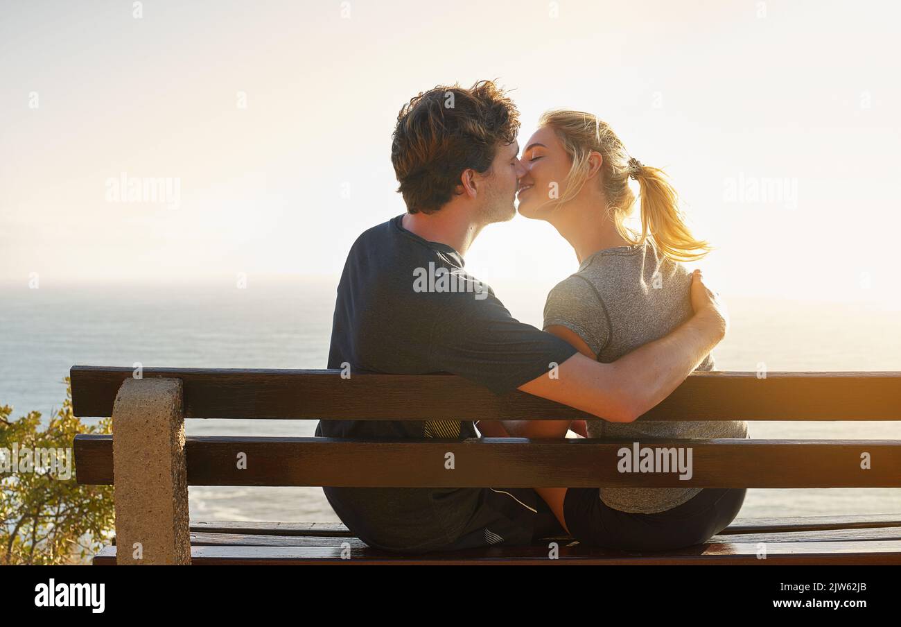 Das Leben ist voller Schönheit. Ein liebevolles Paar sitzt auf einer Bank mit Blick auf das Meer. Stockfoto