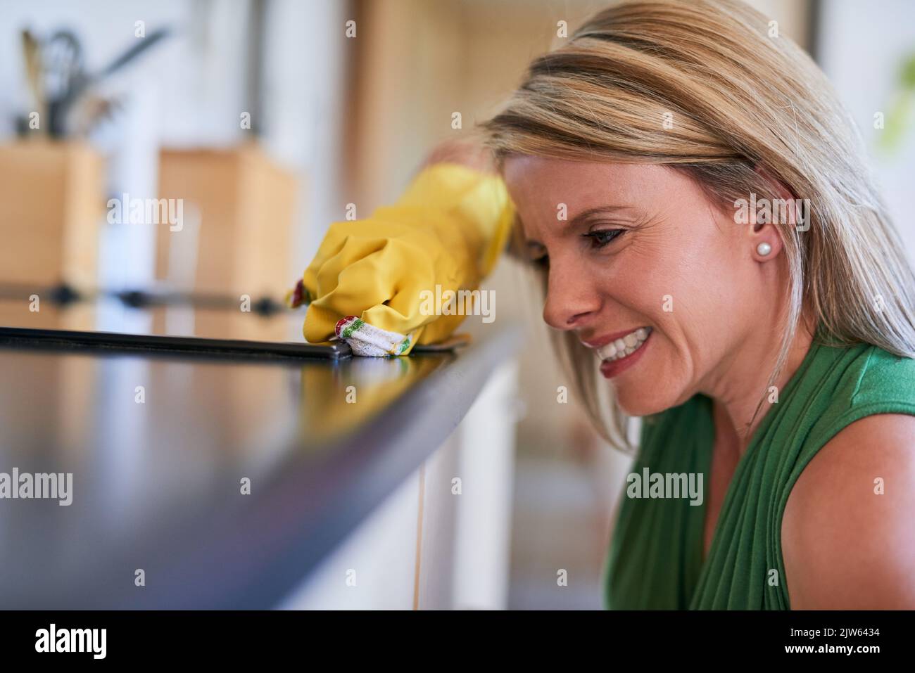 Küchenaufgaben bewältigen. Eine junge Frau, die eine Küchenoberfläche reinigt. Stockfoto