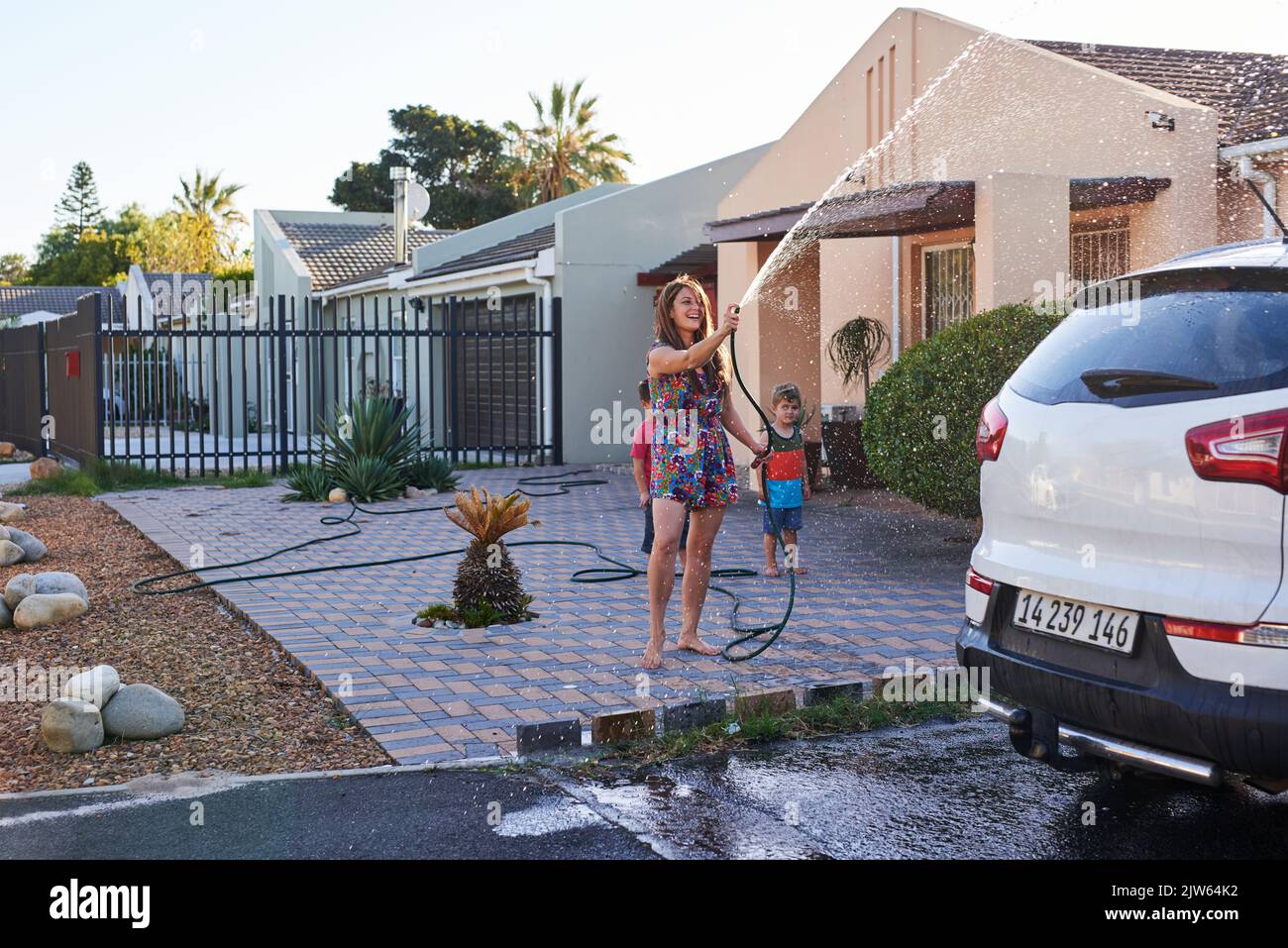 Dieses Auto wird quietschend sauber sein. Eine Familie waschen ihr Auto in der Auffahrt. Stockfoto