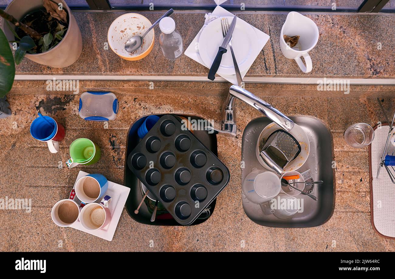 Zeit zum Abwaschen. Ein Spülbecken in der Küche, umgeben von Geschirr. Stockfoto