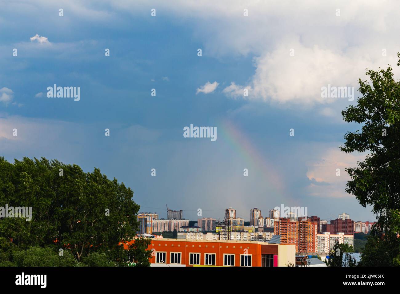 Schöner Regenbogen, der von stürmischem Himmel umrahmt wird, erscheint plötzlich über dem Wohngebiet Tomsk, Russland. Platz für Text kopieren. Stürmisches Wetter, schöne Landschaft. n Stockfoto