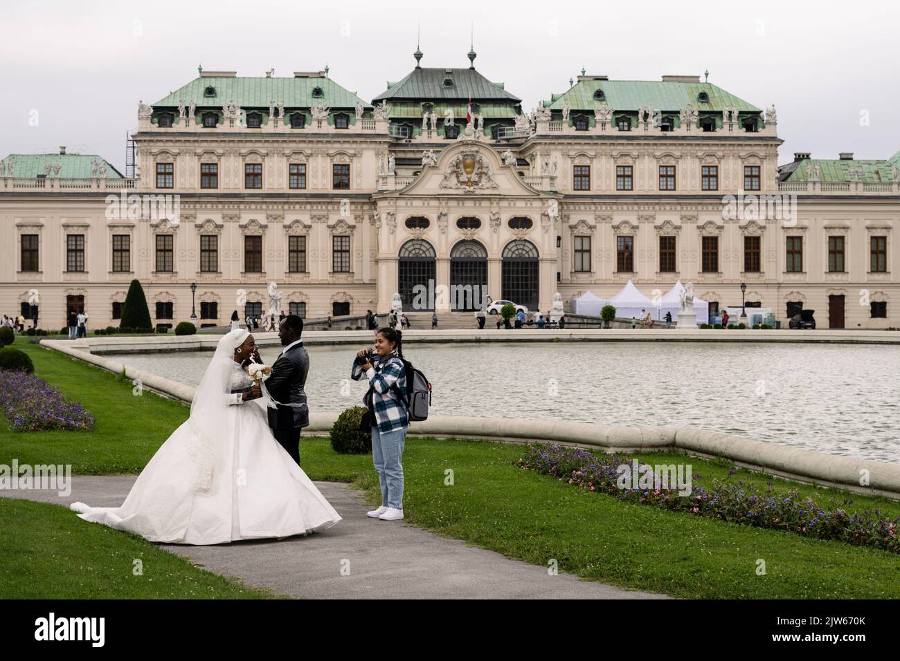 Wien, Österreich - August 6 2022: Braut und Bräutigam in weißem Brautkleid und schwarzem Tuxedo mit Fotograf. Stockfoto
