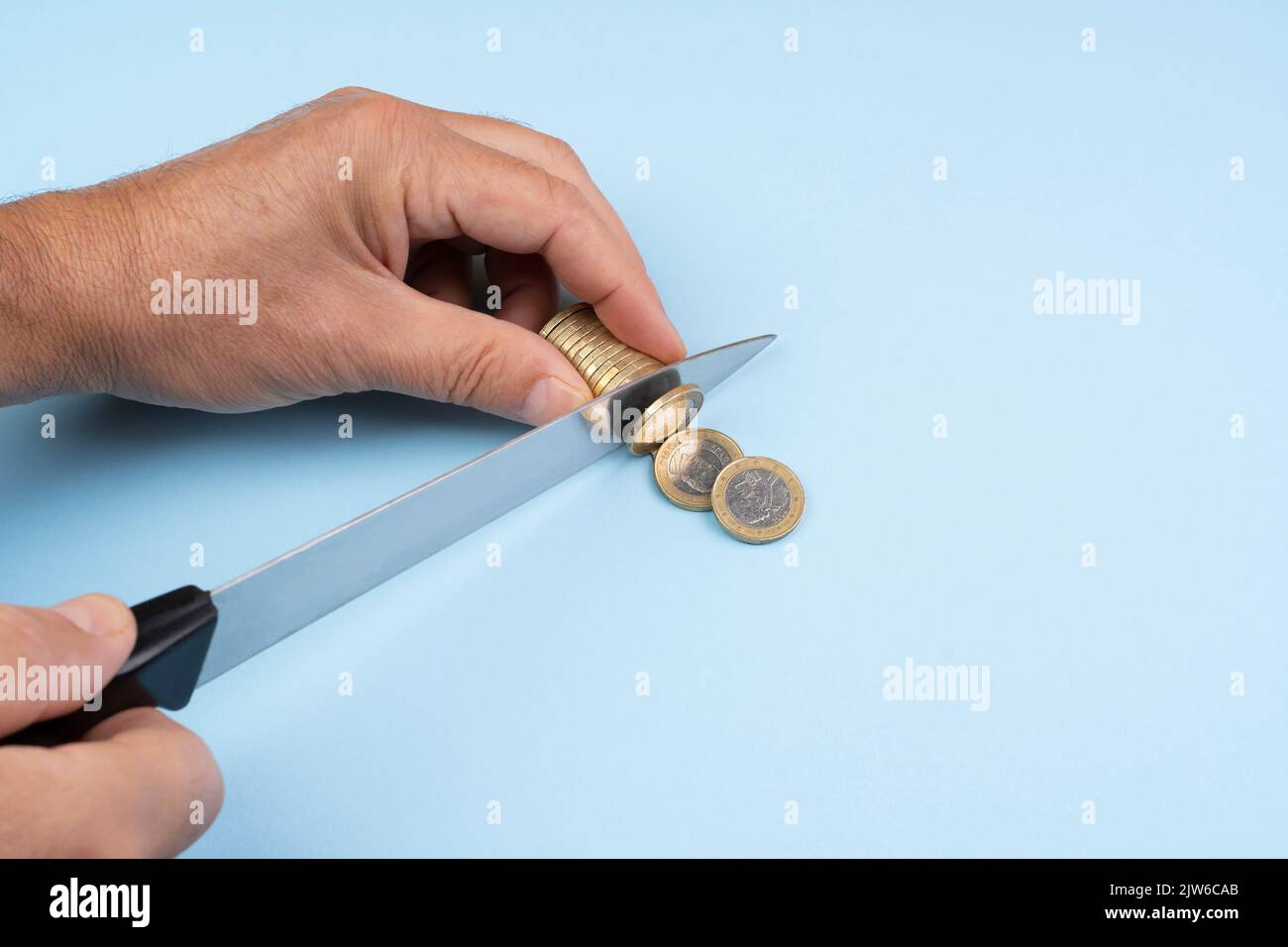 Die Geste des Schneidens einer Euro-Münze mit dem Messer. Konzept der Ratenzahlung von Schulden. Stockfoto