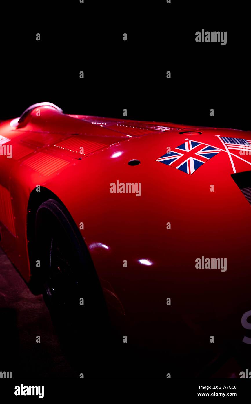 Klassischer roter britischer Rennwagen mit Union Jack Flagge in dramatischer Beleuchtung Stockfoto