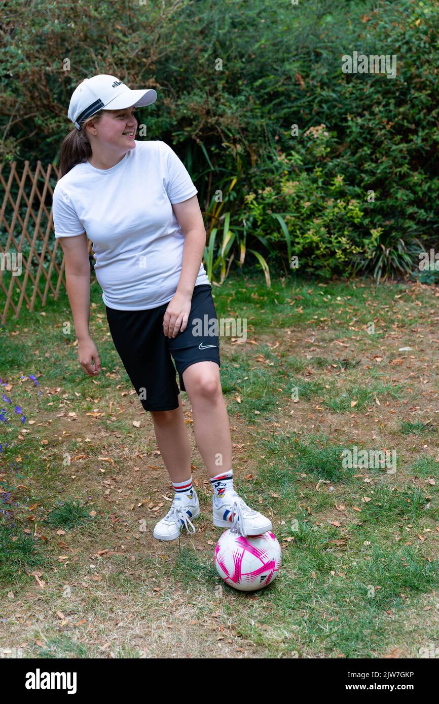 Junge Frau in Sportbekleidung mit Fußball auf dem Gras in Dorset Country Stockfoto