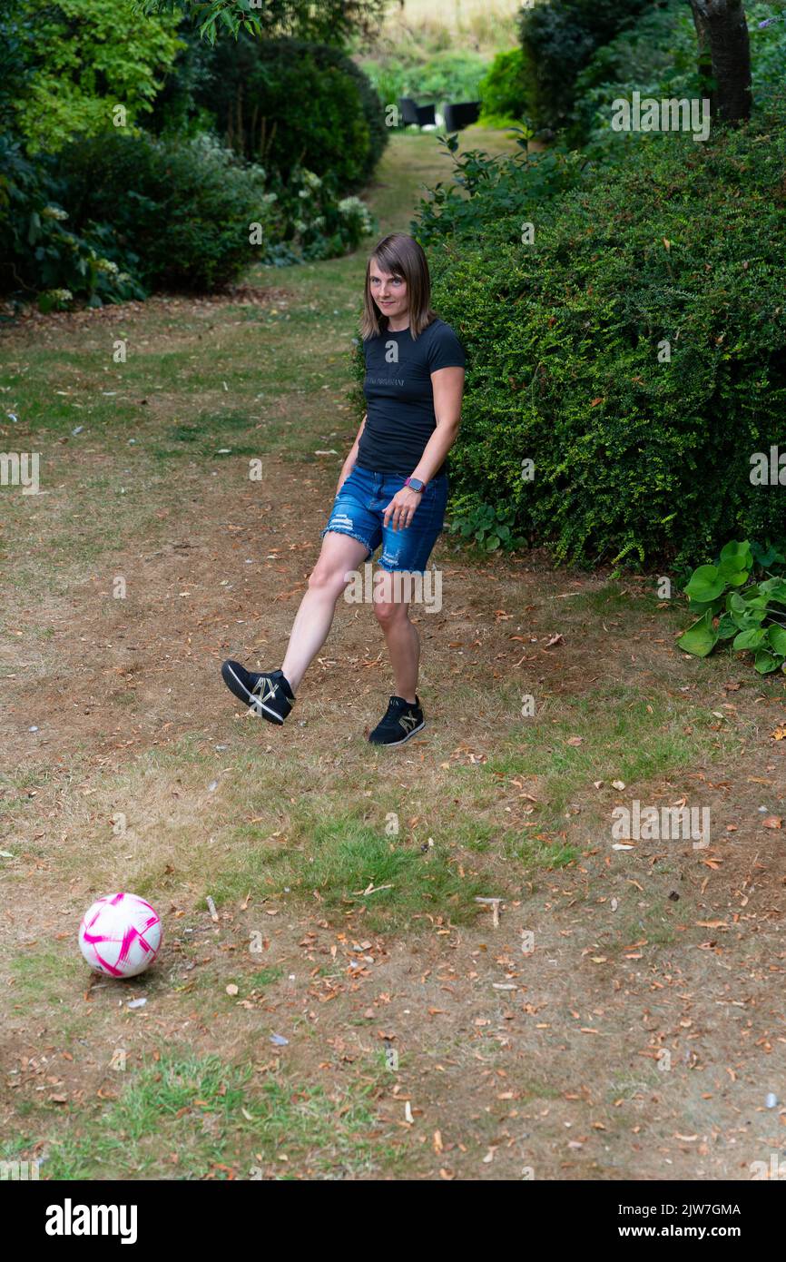 Junge Frau spielt Fußball im Park Stockfoto
