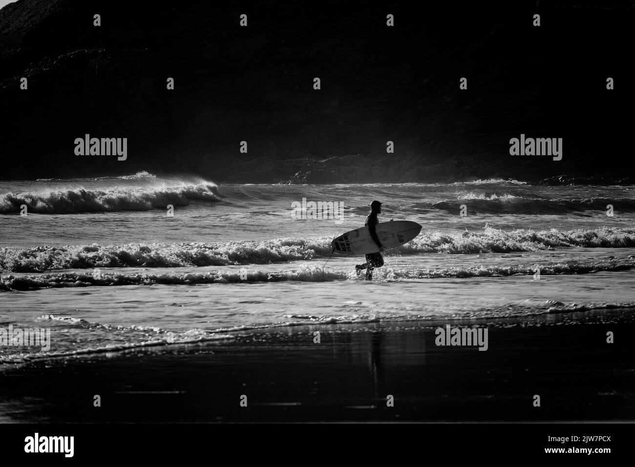 Surfer genießen die Wellen am Gwithian Sands Beach Cornwall. Schwarz und Weiß. Stockfoto