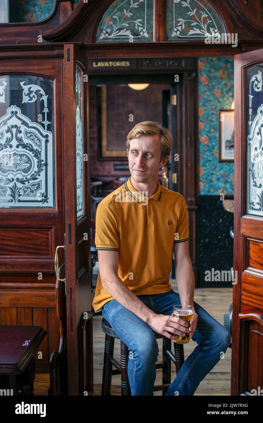 Junger Mann trinkt ein Glas Bier im Boleyn Tavern Pub, West Ham, London, England Stockfoto