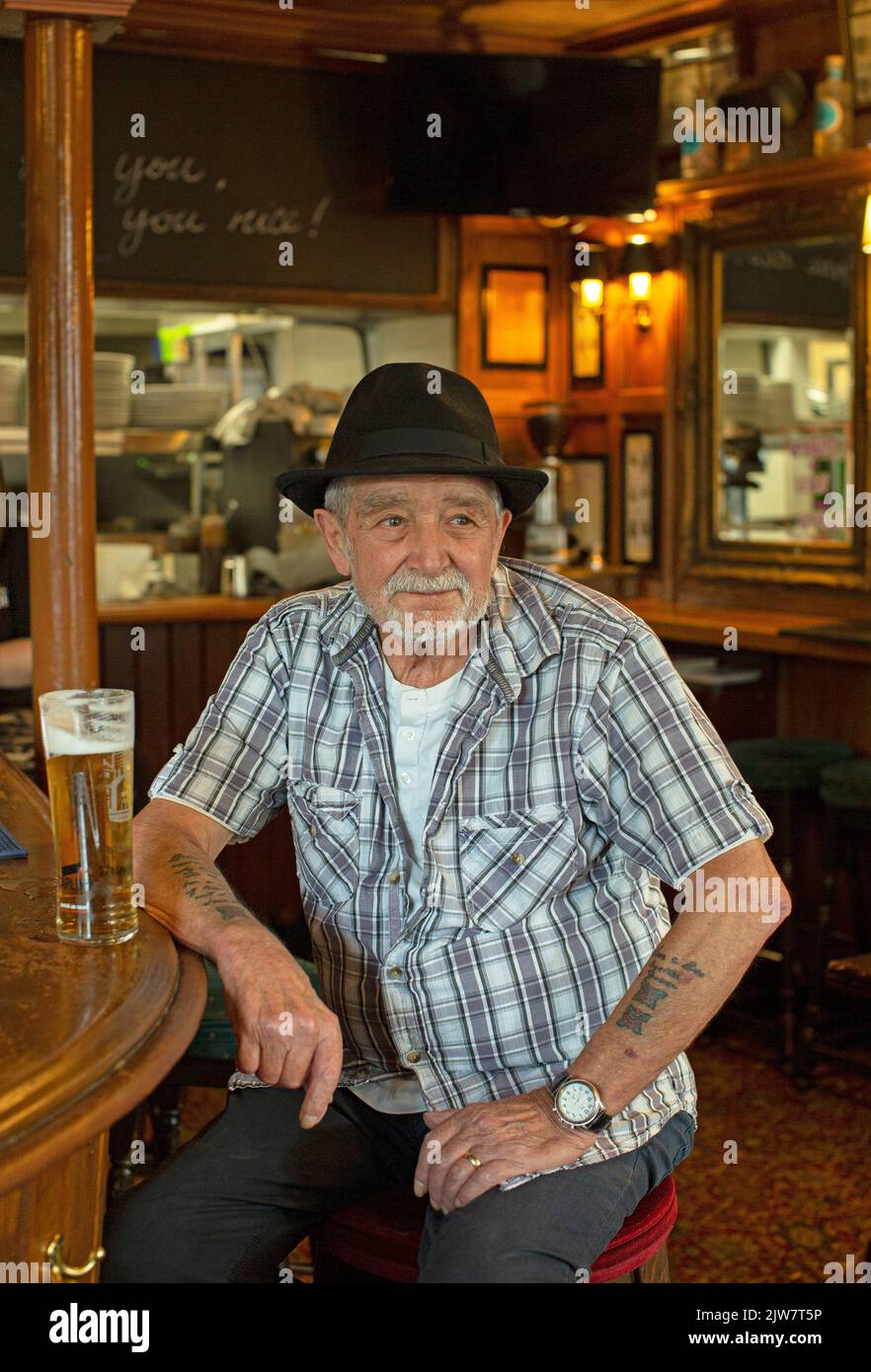 Fröhlicher Mann, der Bier im traditionellen Pub The Eight Bells in Putney, London, Großbritannien, trinkt. Stockfoto