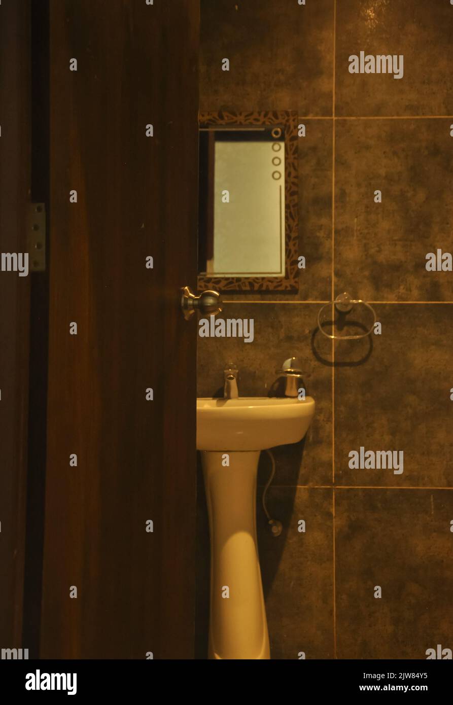 Offene Tür des Badezimmers mit keramischen Waschbecken mit Spiegelblick von außen Stockfoto