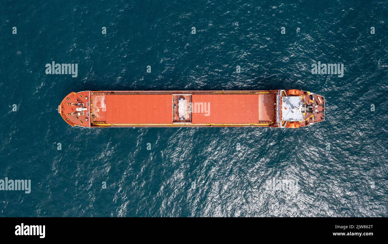 Unbeladenes rotes Frachtschiff, das in ruhigem Wasser verankert ist. Stockfoto