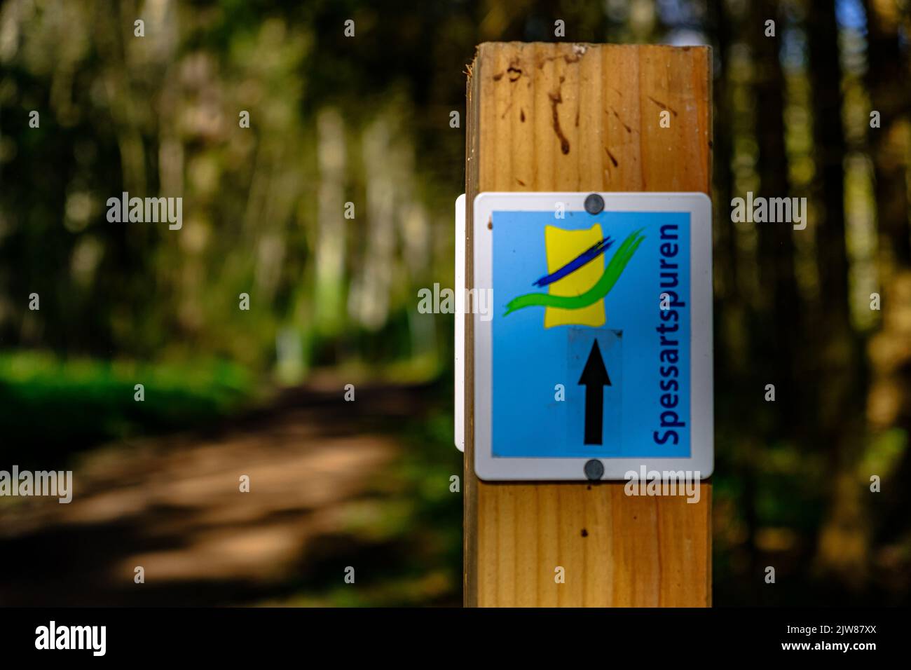 Eine Nahaufnahme eines Wegweihens auf dem Holz mit Bäumen verschwommen Hintergrund Übersetzung fixiert - spessart Spuren Stockfoto