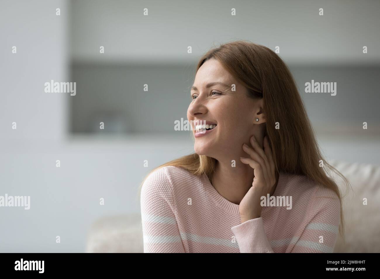 Glücklich verträumt hübsche 30s Frau in lässig sitzen auf Couch Stockfoto