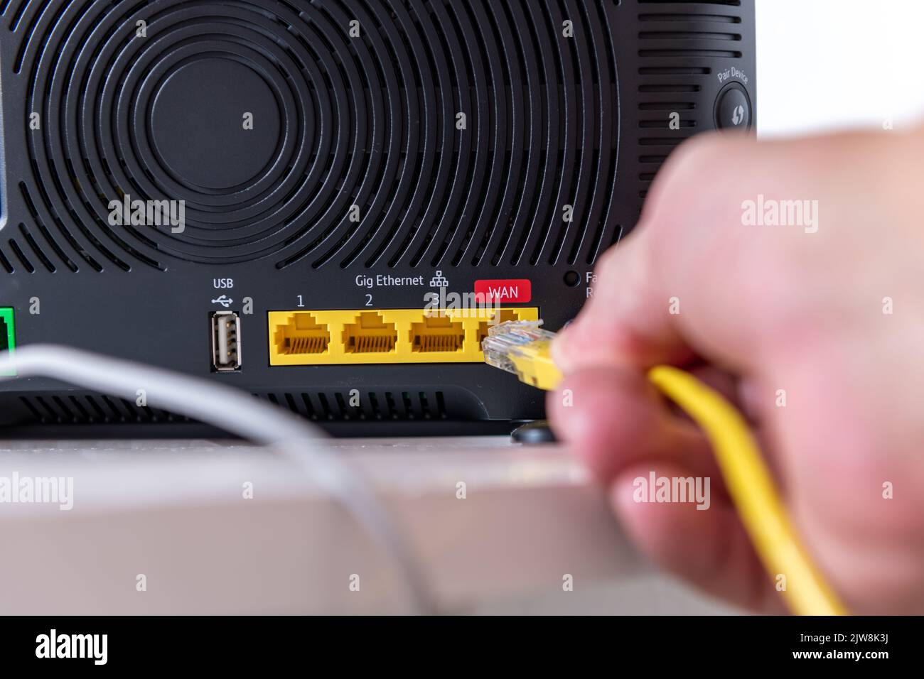 Eine Person, die ein Gerät mit einem Internet-Router verbindet. Stockfoto