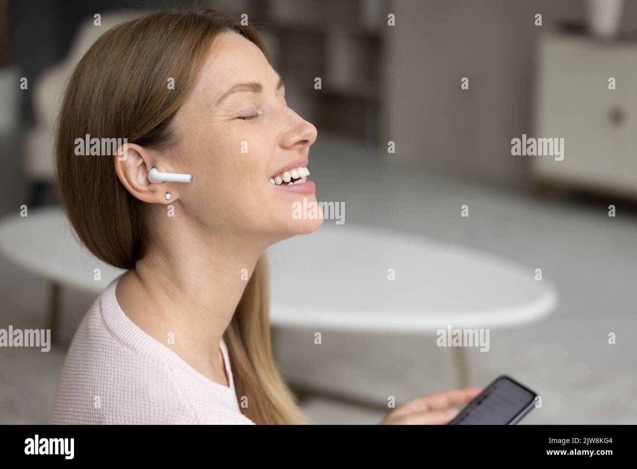 Glückliche, aufgeregt tausendjährige Frau, die inspirierende Musik hört Stockfoto