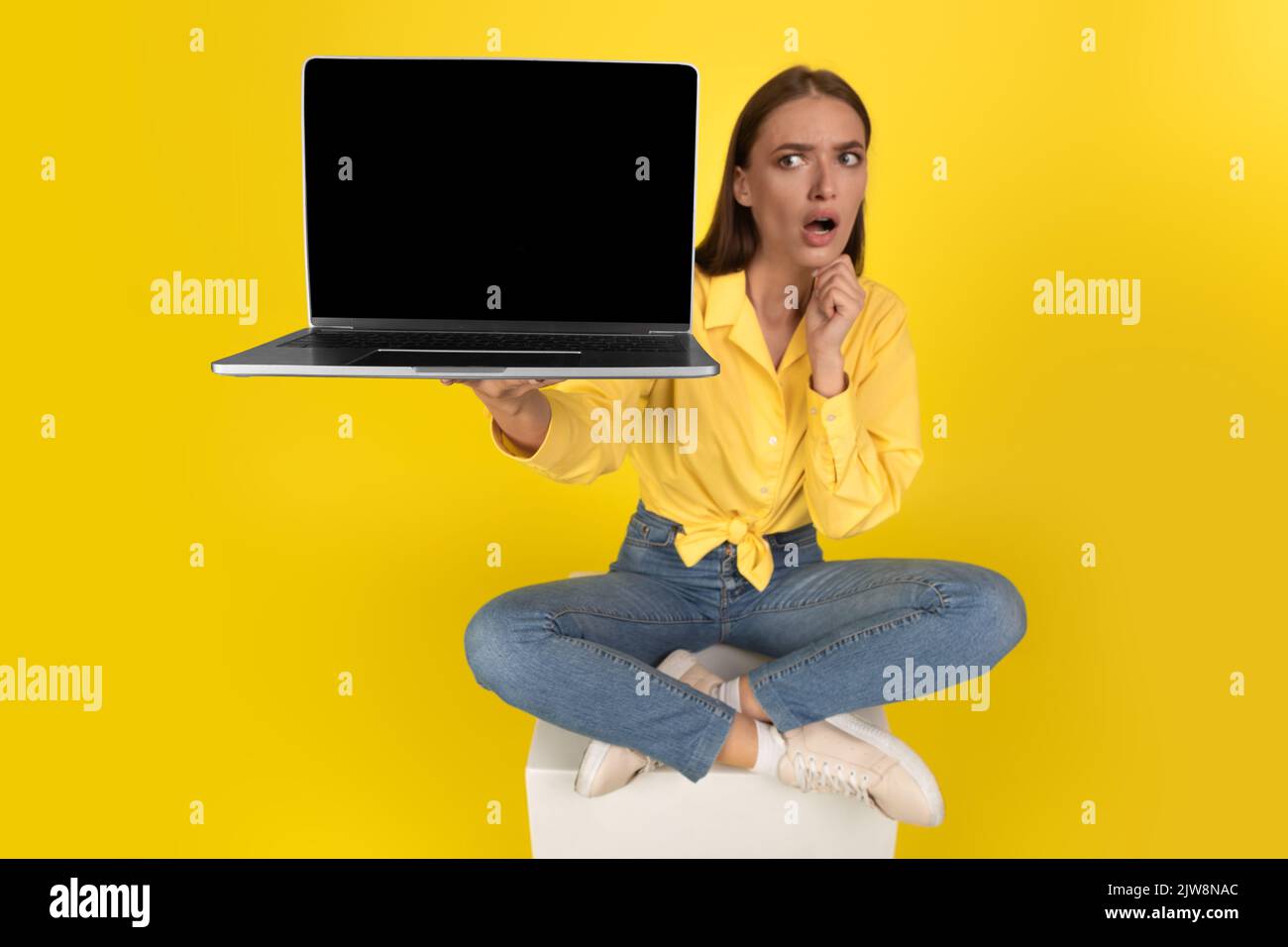 Schockiert Frau Zeigt Laptop Unbeschriftet Bildschirm Sitzt Über Gelbem Hintergrund Stockfoto