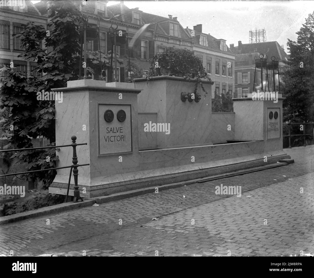 Bild der gegenüberliegenden Utrechtse Fabrik für Silberarbeiten C.J. Begeer (Oudegracht Tolsteegzijde 17) Brunnen, der anlässlich der Feierlichkeiten zum 54.-jährigen Bestehen der Universität in Utrecht mit dem Thema der triumphalen Reise des Germanicus in Rom im Jahr 17 n. Chr. nach Chr. erstellt wurde Die Adresse Oudegracht Tolsteegzijde 17 wurde 1917 in Oudegracht 187 geändert. Stockfoto