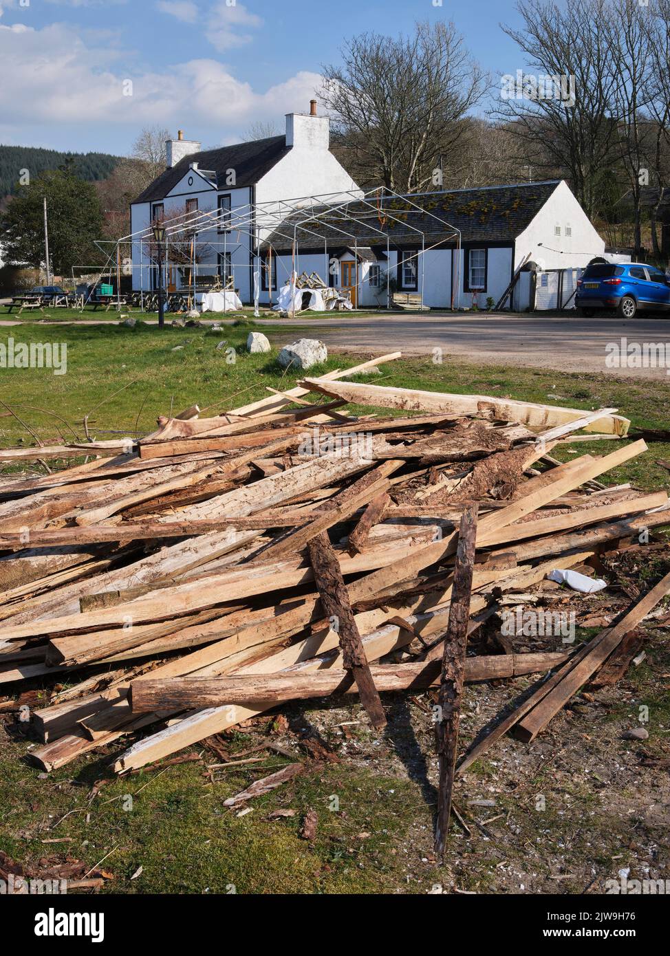 Ein Holzstapel und ein Rahmen bedecken die Vorderansicht des Otter Ferry Inn über die Küste von Loch Fyne Stockfoto