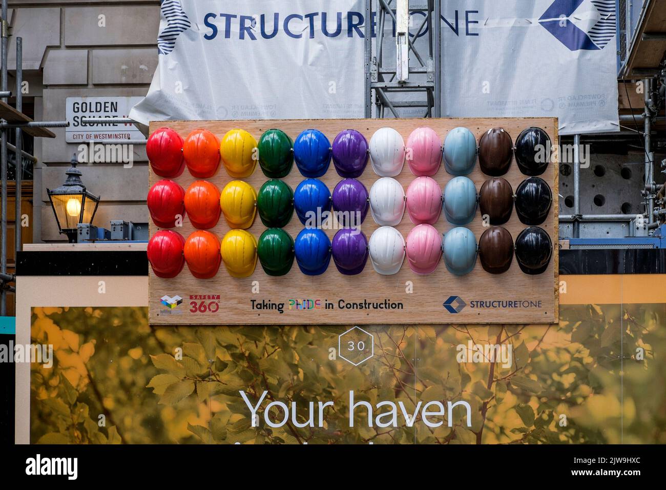 Die Präsentation von Arbeiterhüten in Regenbogenfarben, die das Konzept der Inklusivität innerhalb der Beschäftigten der Bauindustrie darstellen, London, Großbritannien. Stockfoto