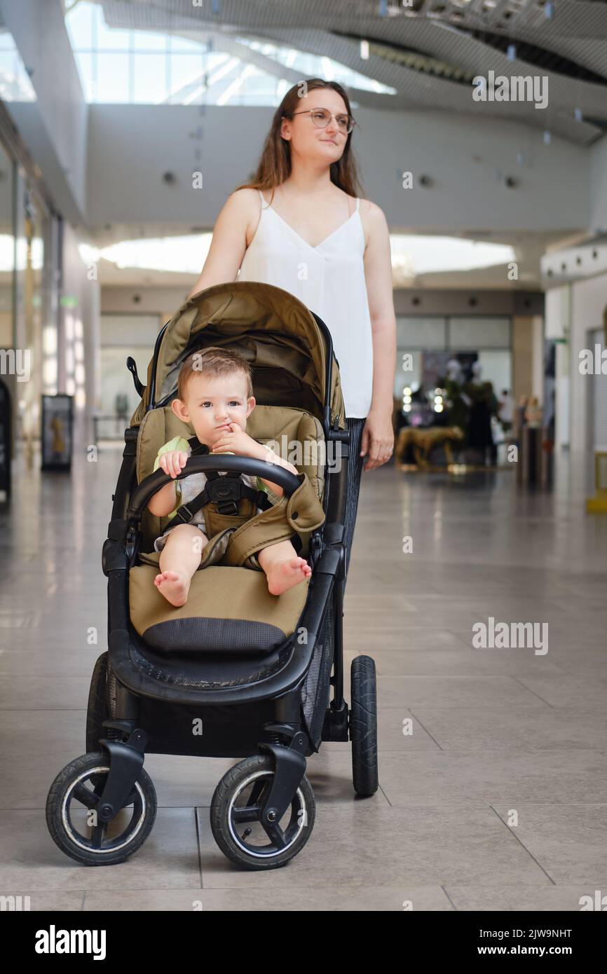 Eine Mutter und ein Kind in einem Kinderwagen stehen vor einem Geschft in  einem Einkaufszentrum. Mama einkaufen mit einem Kleinkind Baby junge  Stockfotografie - Alamy